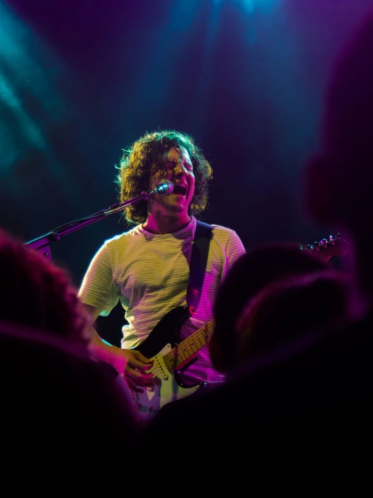 Singer-songwriter playing acoustic guitar under a single spotlight